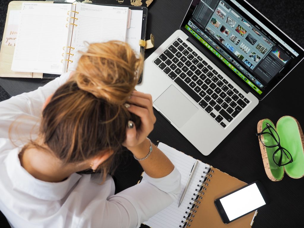 Woman sitting at her computer feeling stress and anxiety and wondering "What is high-functioning anxiety?"