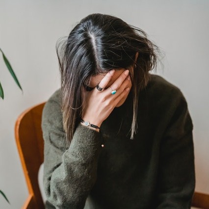 Woman with her hand on her forehead worried.