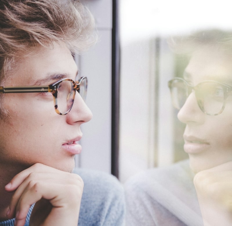 young male looking out a window