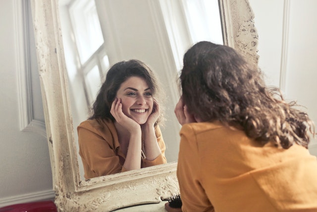photo of a woman staring at herself in the mirror